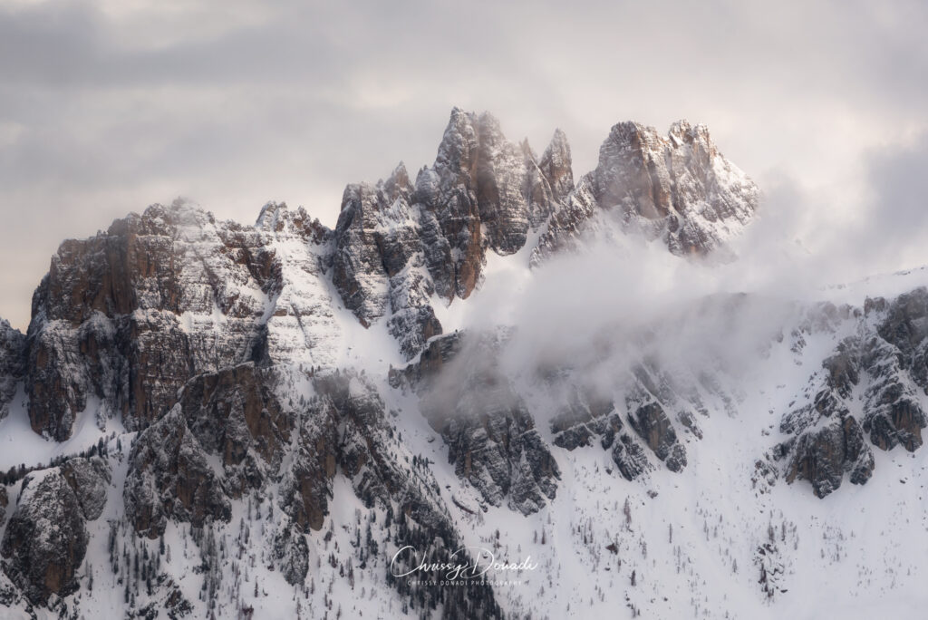 Landscape photography image of the Dolomite mountain peaks receiving their first moment of sunlight as the clouds begin to dissipate