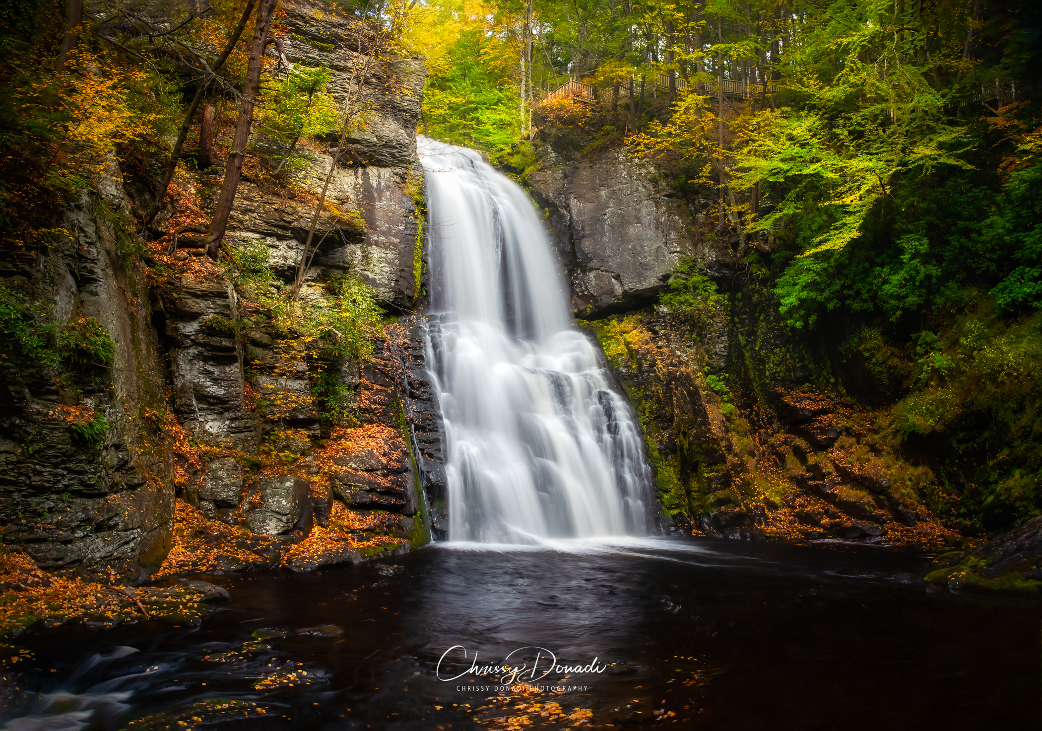 Fall photography of a waterfall surrounded by fall foliage.